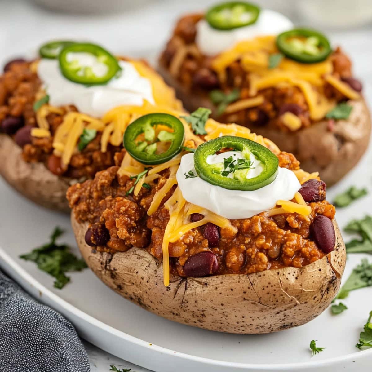 Baked potatoes split open, filled with spicy chili, ground beef, kidney beans and topped with sour cream, shredded cheese and jalapenos.