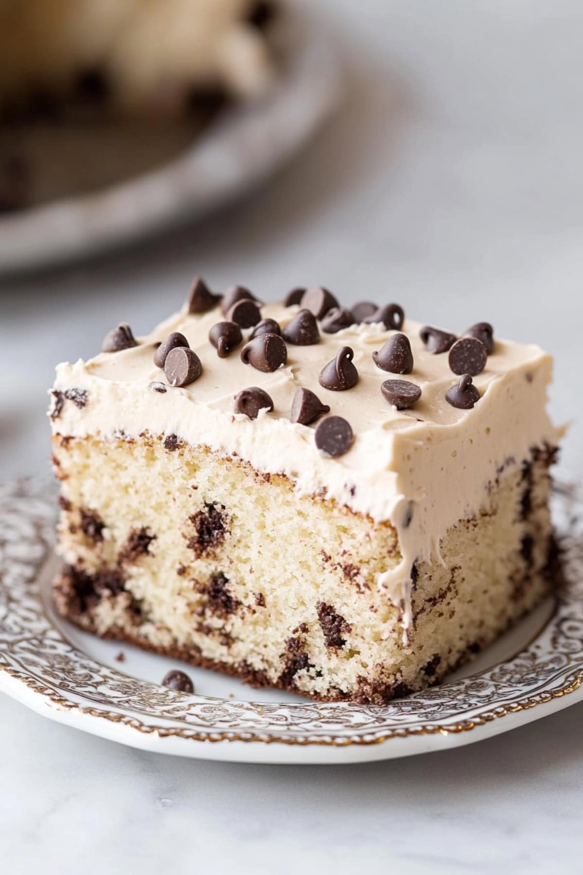 Slice of cake with white frosting and chocolate chips.