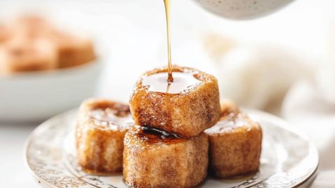 maple syrup drizzled over bunch of cinnamon French toast bites served in a plate.