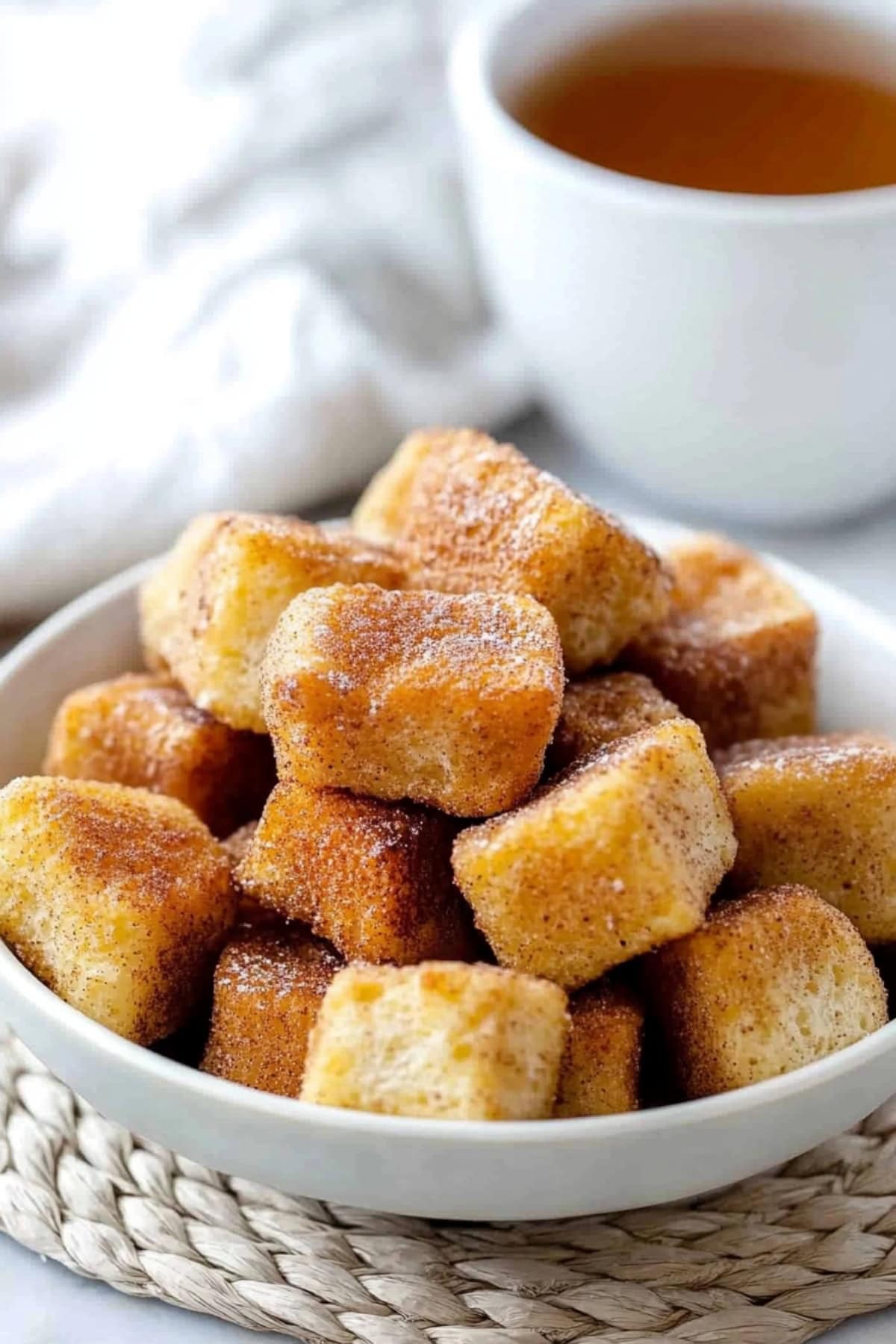 Cinnamon French toast bites served in a bowl with tea on the side.