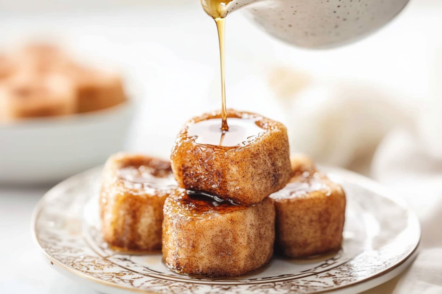 maple syrup drizzled over bunch of cinnamon French toast bites served in a plate.