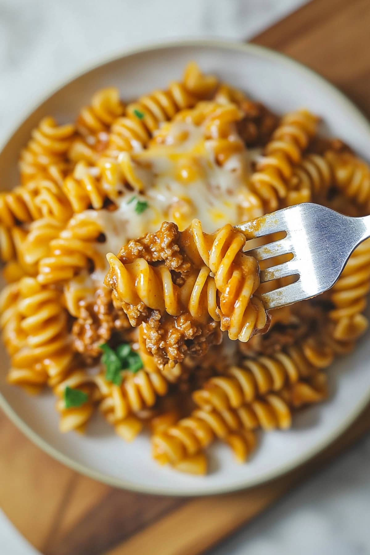 Fork lifting a scoop of enchilada pasta from serving in a plate.