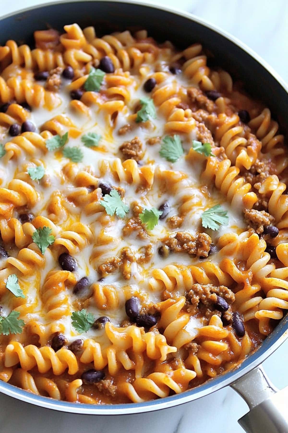 Cheesy and saucy enchiladas pasta cooked in a skillet pan.