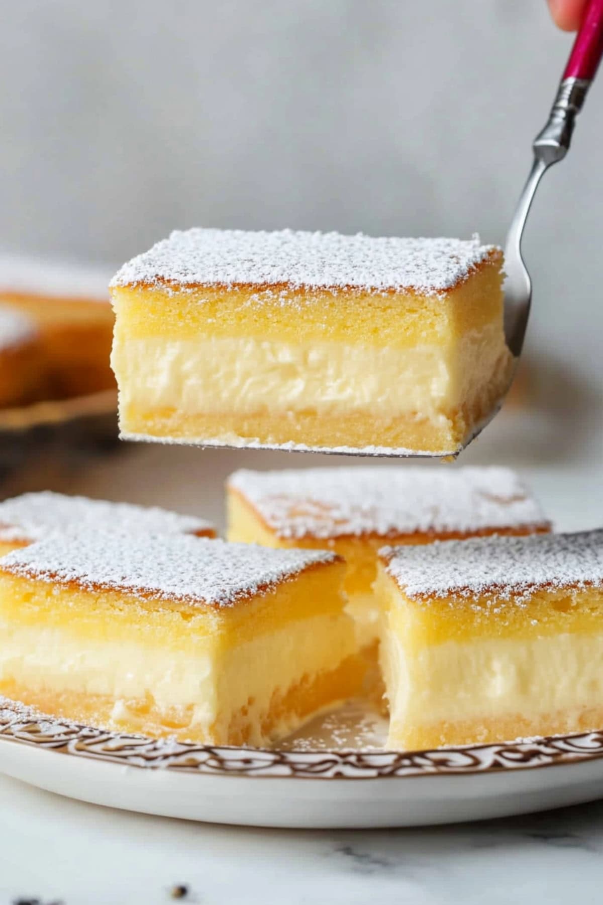 Slices of magic custard cake topped with dusted powdered sugar on a plate, side view