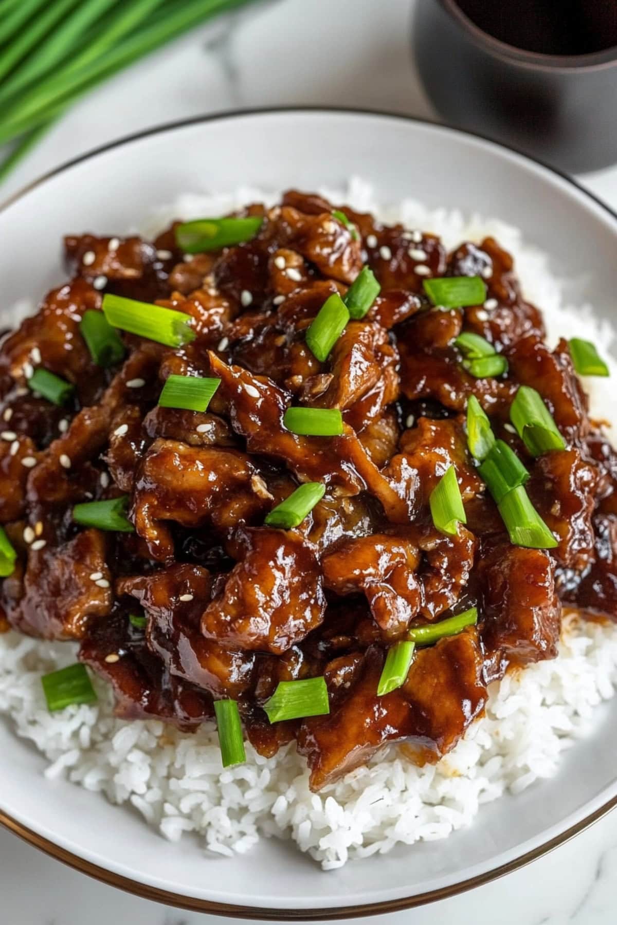 Mongolian pork served on top of rice in a white plate.