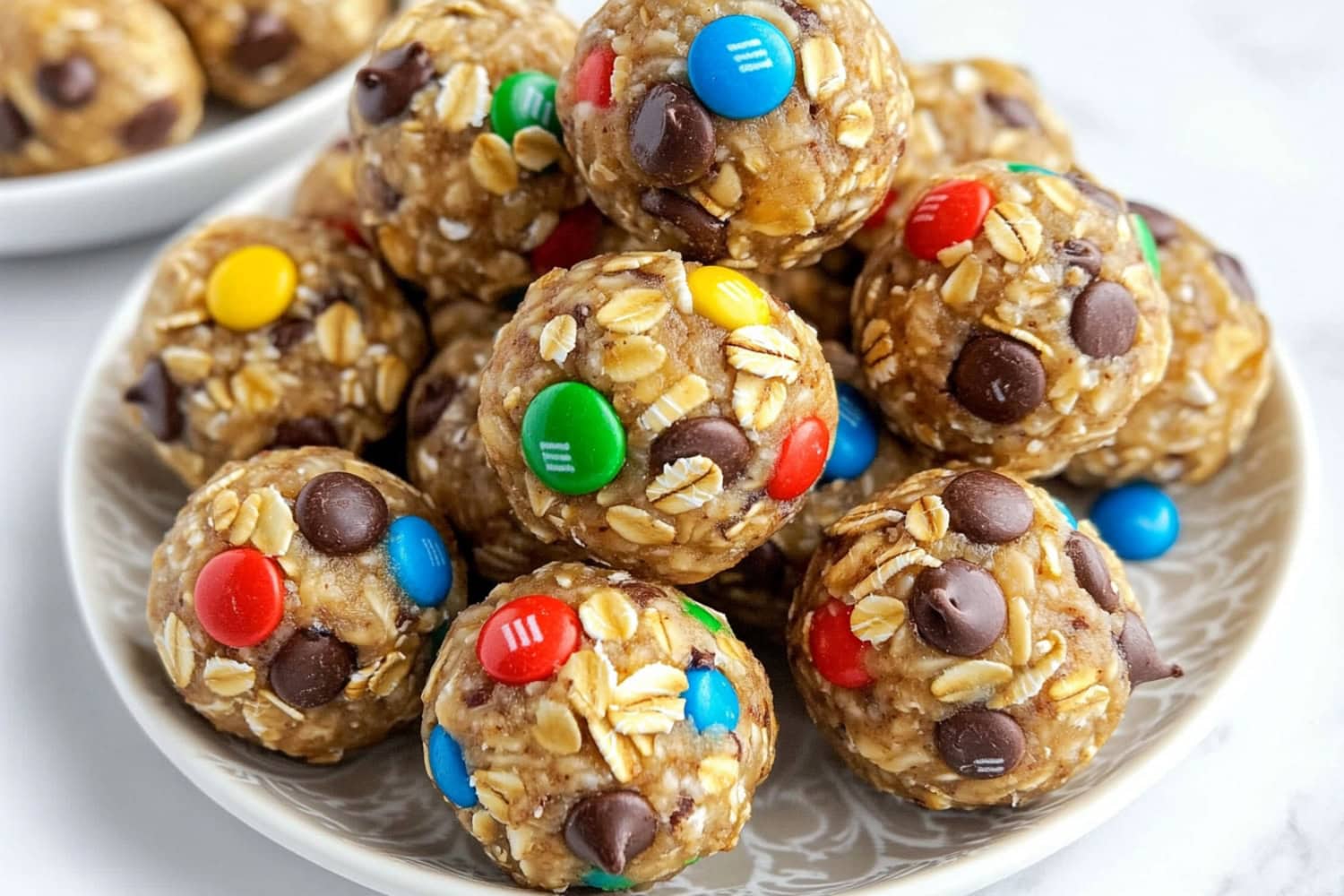 A plate filled with chewy monster cookie balls made from oats, M&Ms, peanut butter, and chocolate chips.