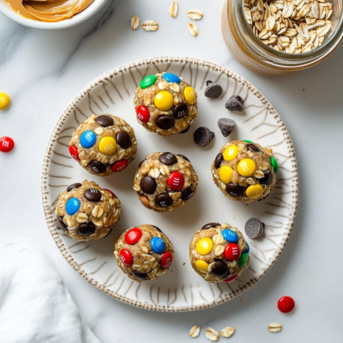 A plate of monster cookie balls with oats, chocolate chips, peanut butter, and M&Ms, ready to enjoy.