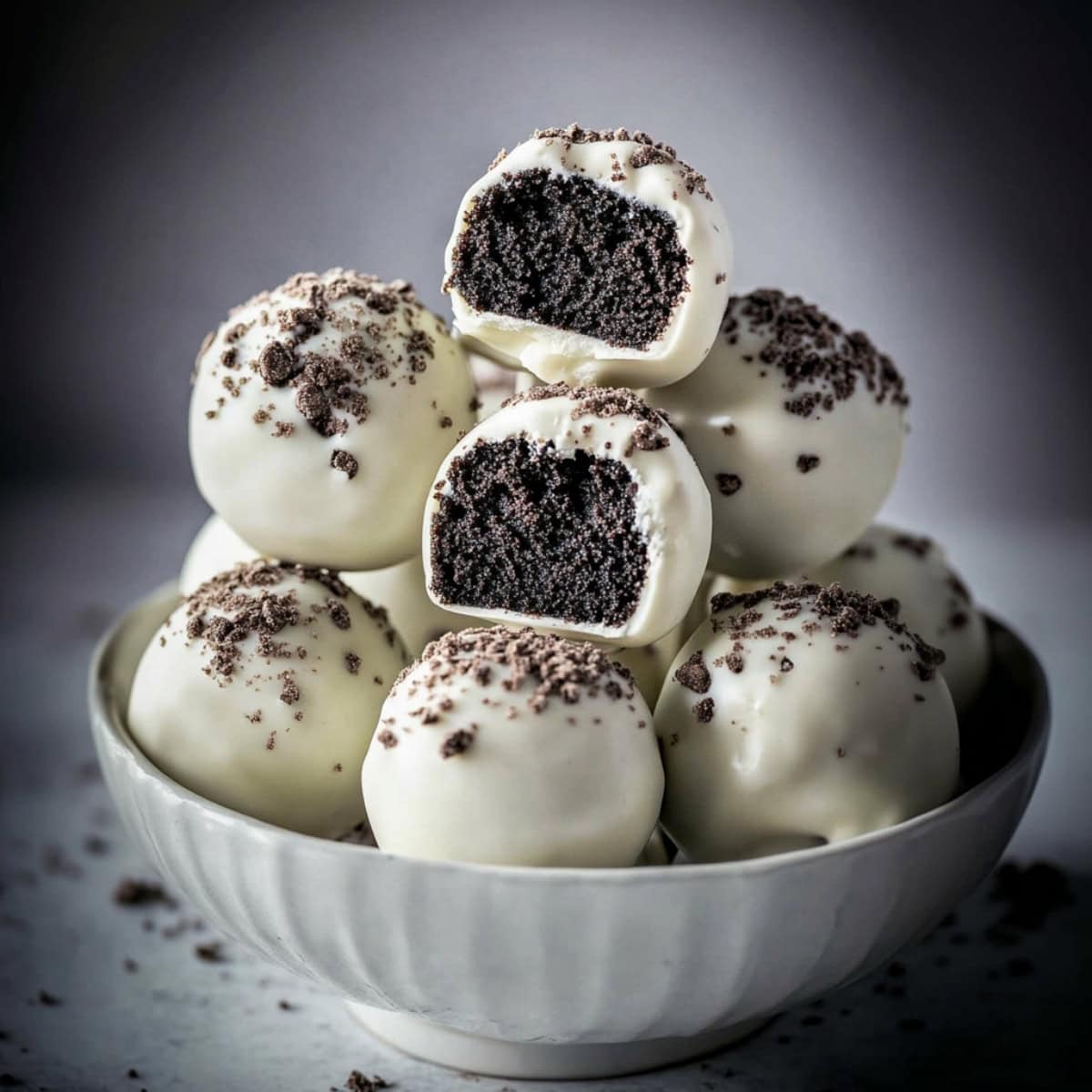 Bunch of Oreo cake pop stacked on top of each other in a white bowl.