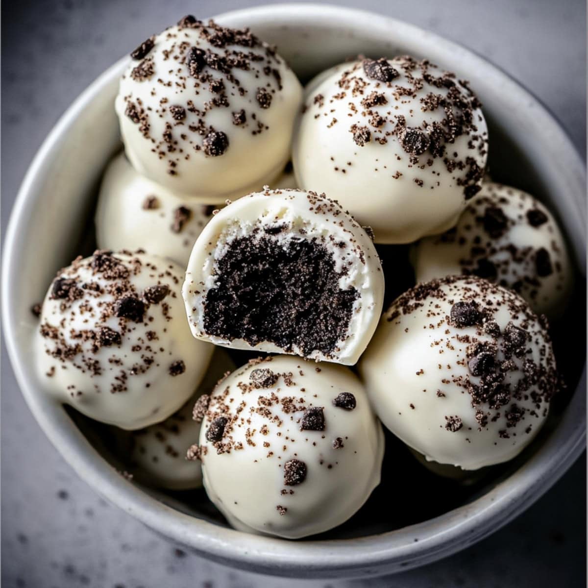 White chocolate coated Oreo cake pops arranged in a white plate.