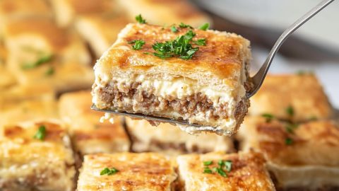 Pie ladle lifting a square slice of sausage cream cheese.