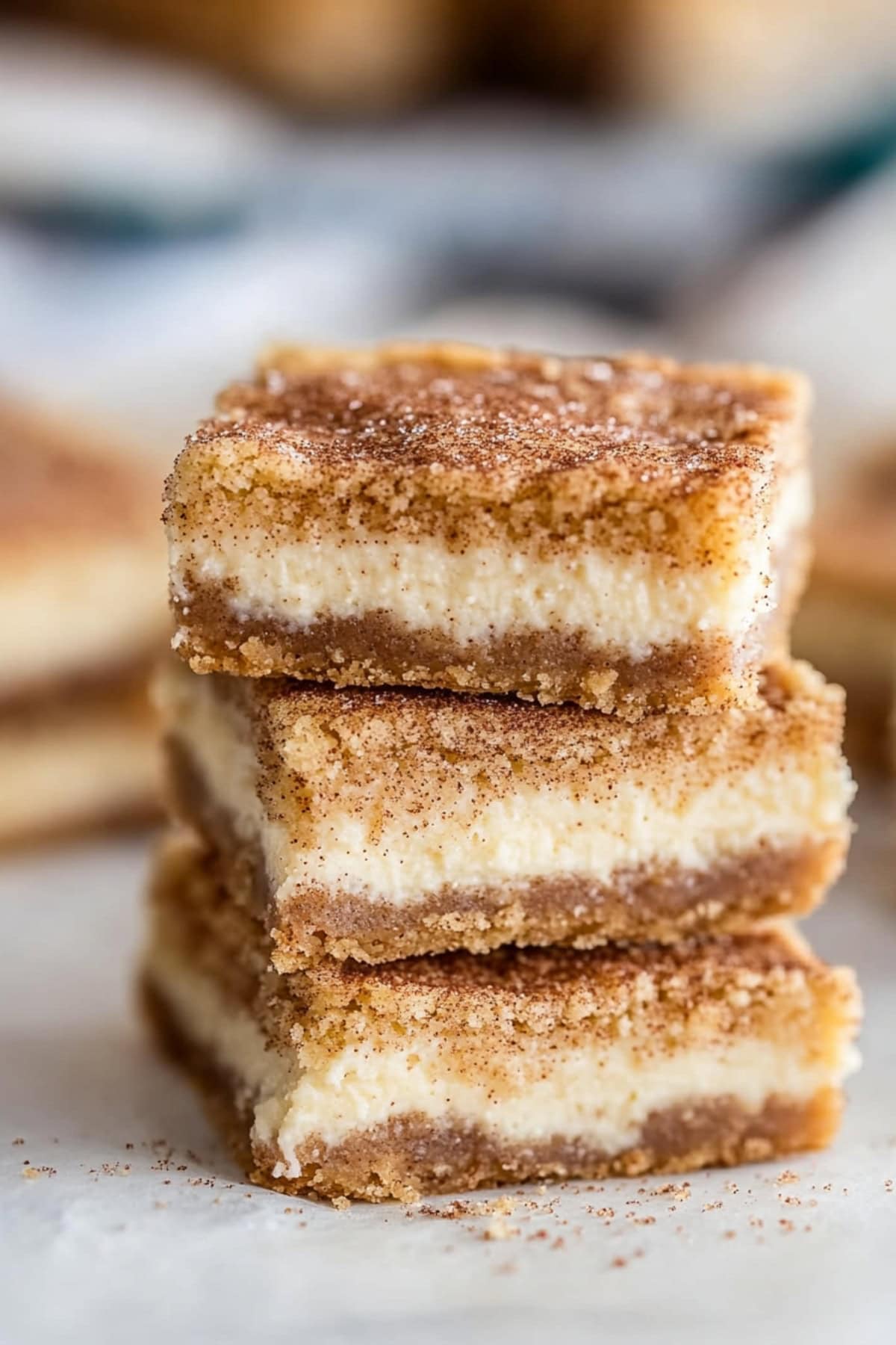 Snickerdoodle cheesecake bars stacked on top of each other.