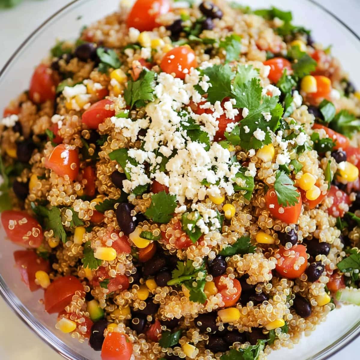 Close-up of a glass bowl of Southwest quinoa salad with black beans, tomatoes and corn.