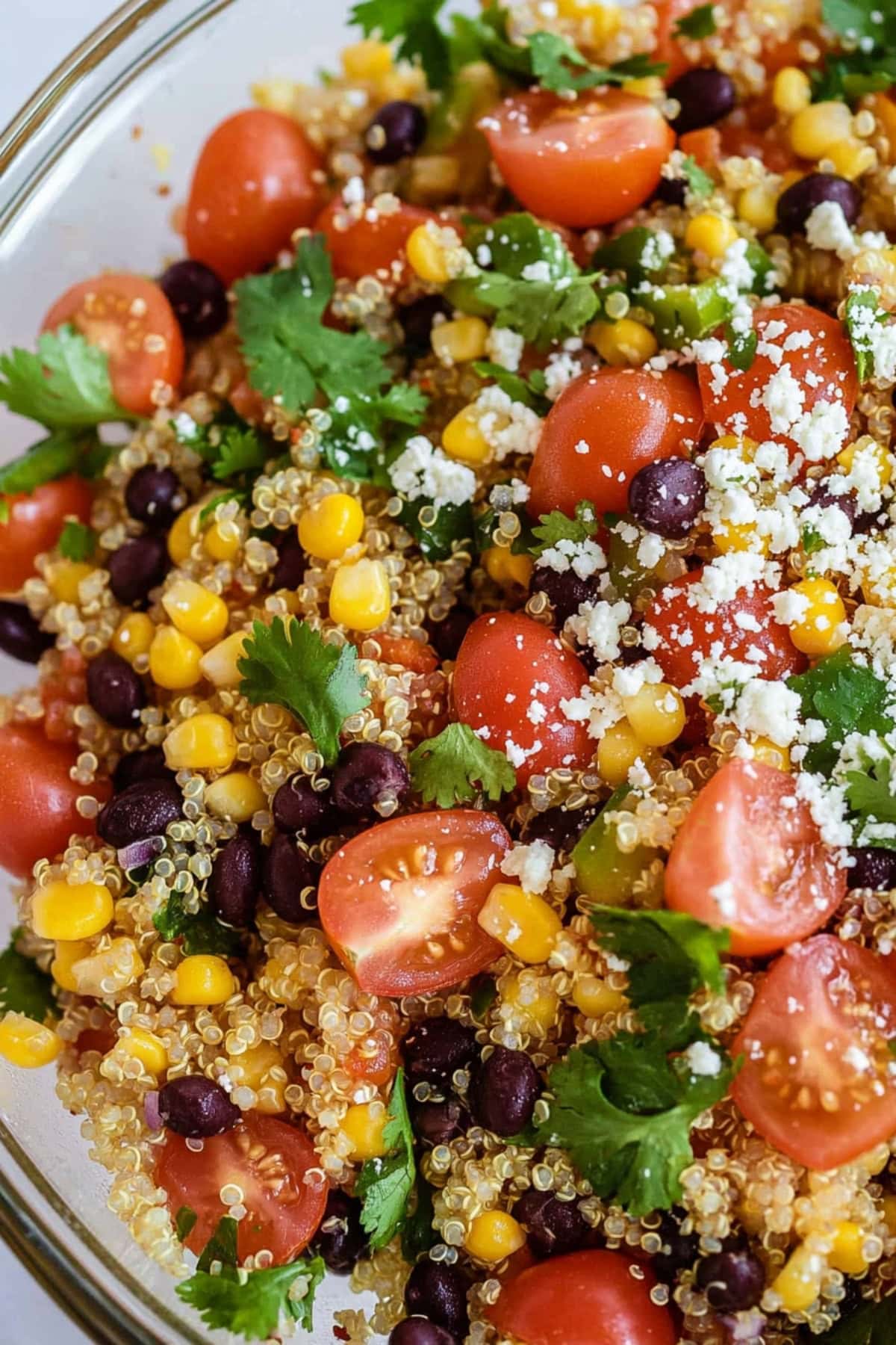 Southwest quinoa salad with black beans, tomatoes and corn in a glass bowl.