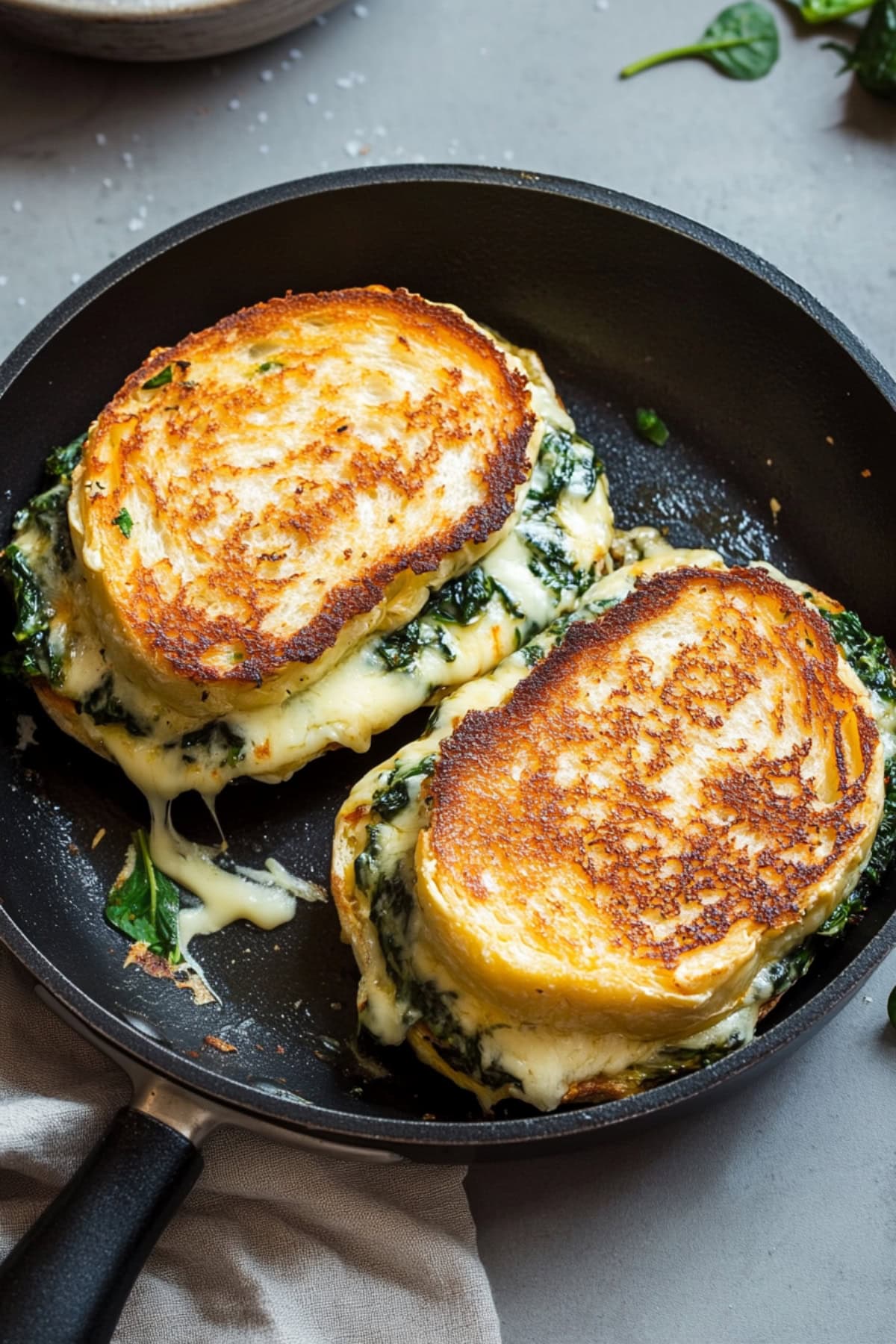 Skillet pan with grilled cheese filled with melted cheese, artichoke and spinach.