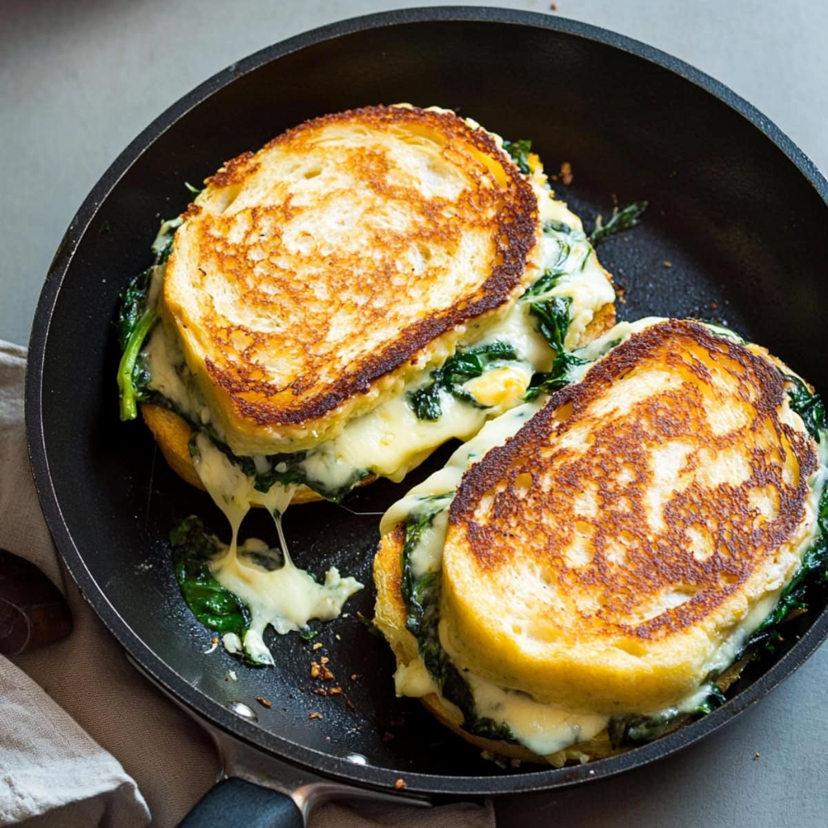 Grilled cheese with spinach and artichoke in a skillet pan.