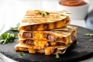 Savory and mouthwatering homemade steak quesadillas in a wooden board.