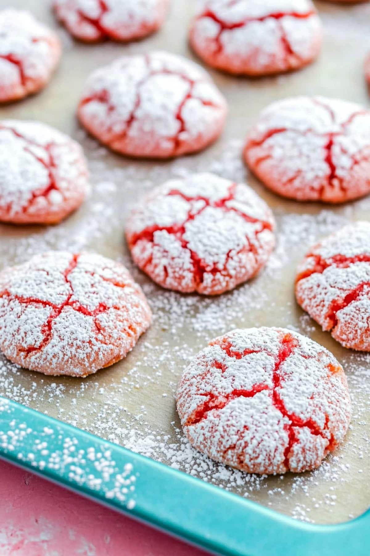 Strawberry cookies on a baking tray covered in powdered sugar