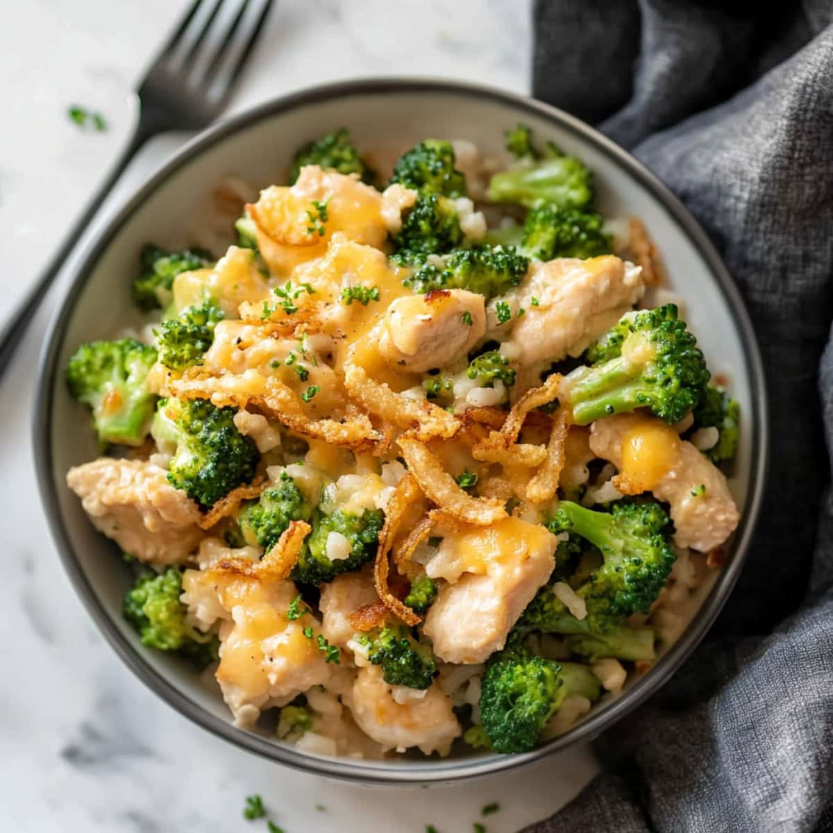 An overhead view of chicken broccoli rice with fried onions in a bowl.