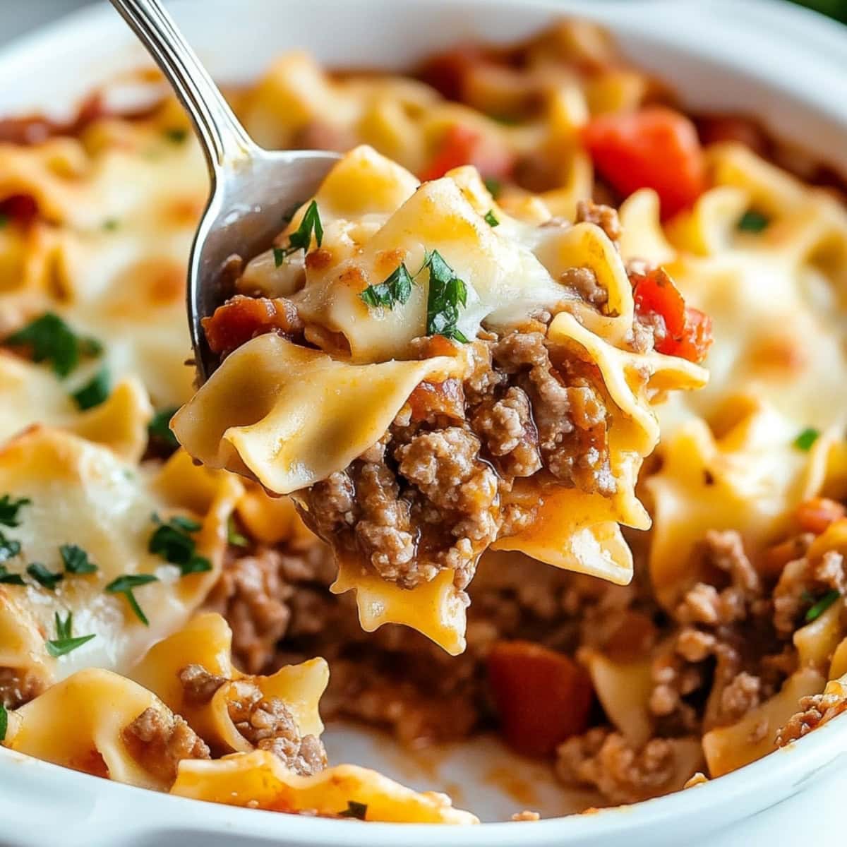 A close-up of a spoonful beef lombardi casserole featuring wide egg noodles.