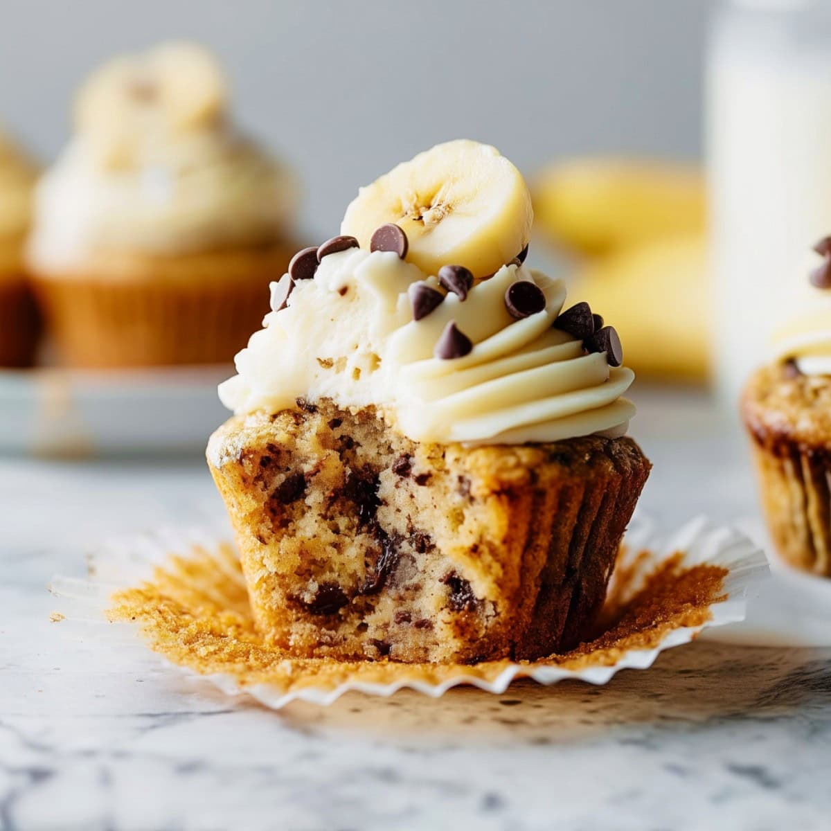 A bitten-into Banana Chocolate Chip Cupcake with Cream Cheese Frosting