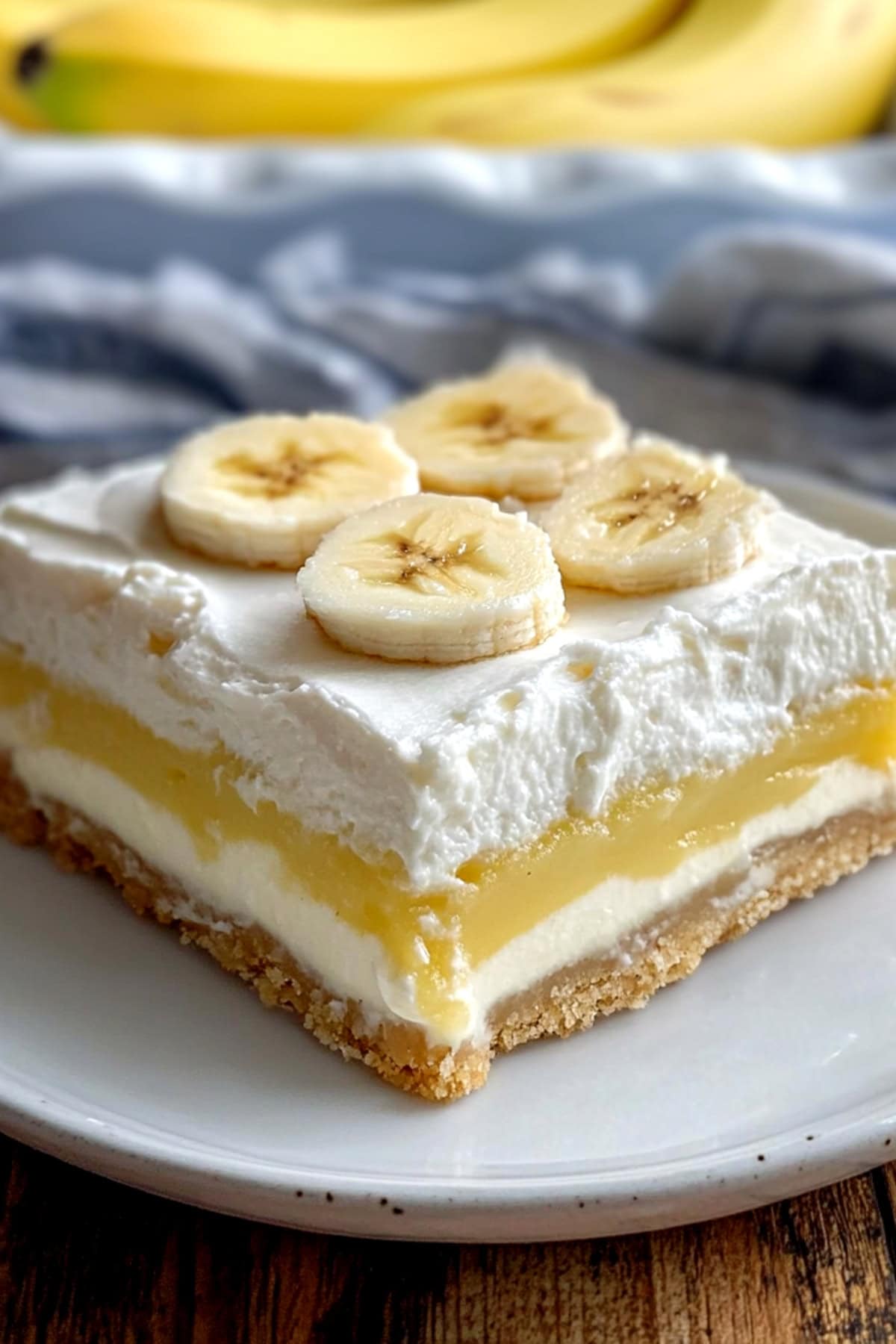 Banana cream pie bars on a serving plate with pudding and cream cheese layer.