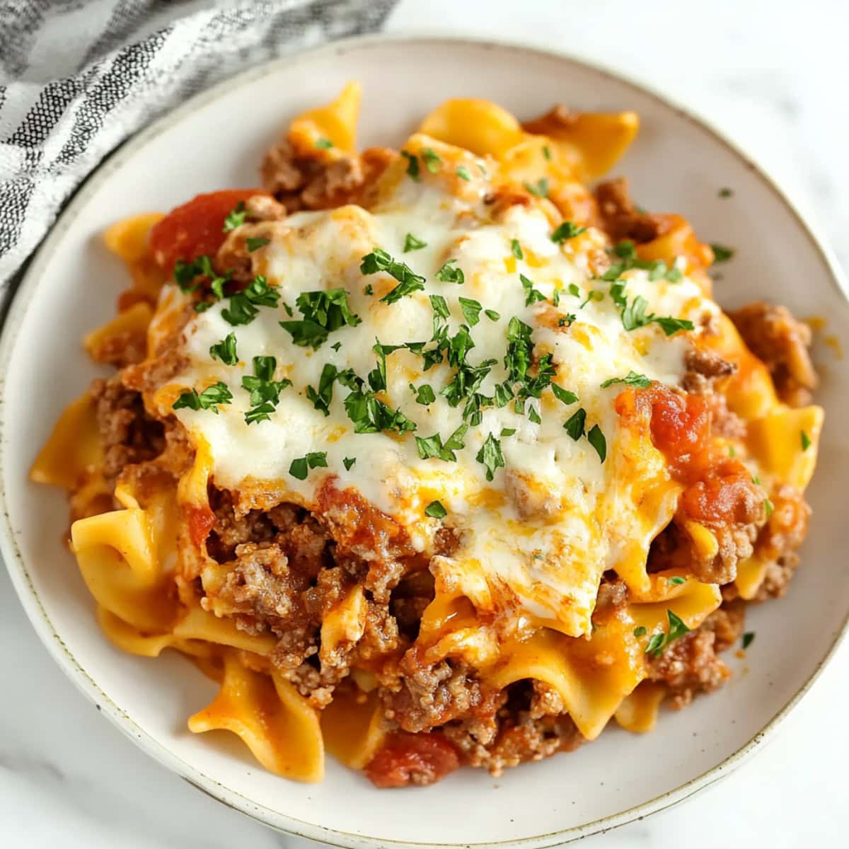 Cheesy homemade beef Lombardi with tomatoes in a white plate.