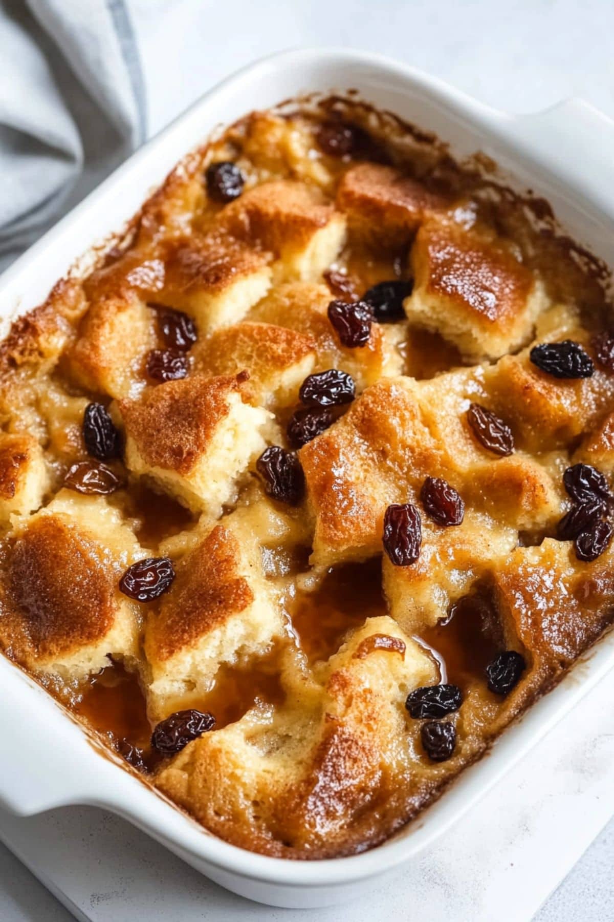 Bread pudding with raisins and brown sugar syrup baked in a rectangular baking dish.