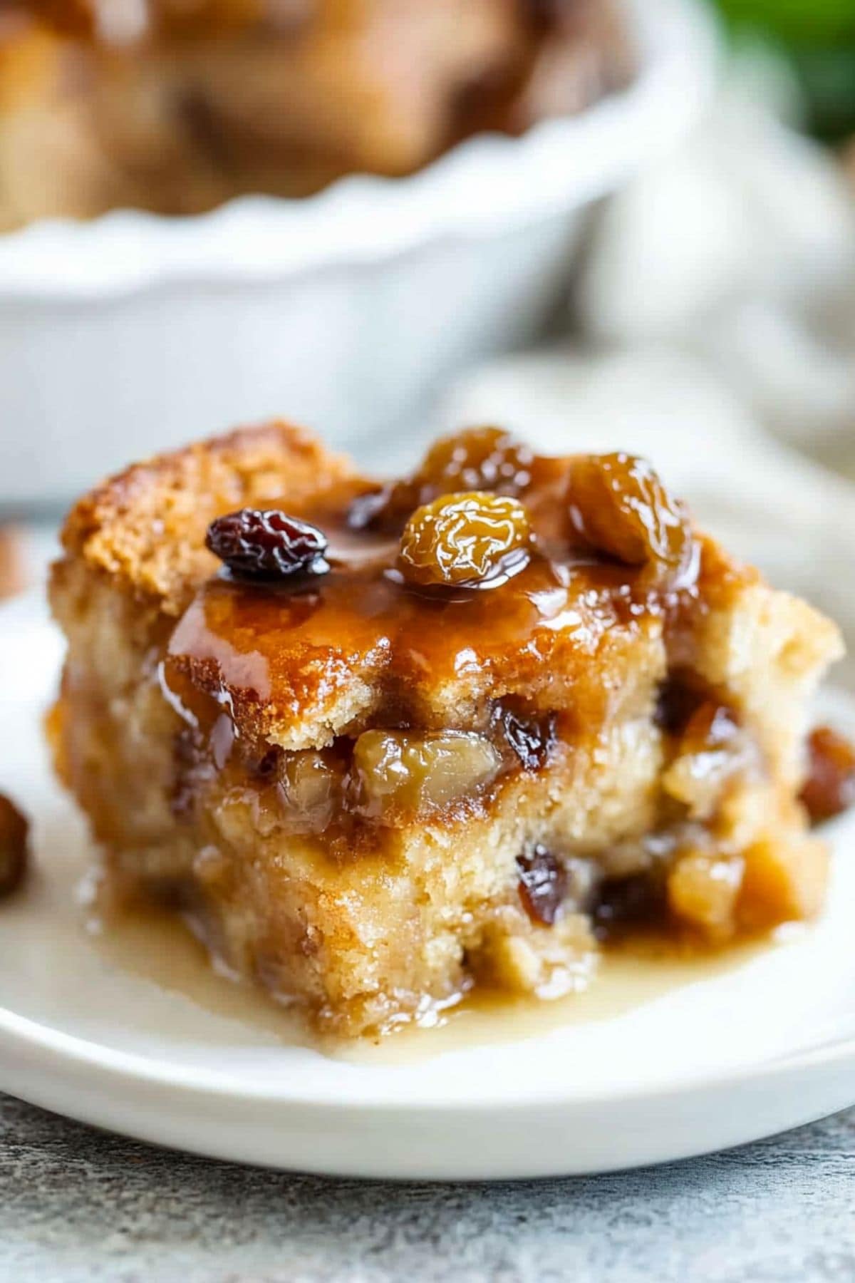 A serving of  bread pudding with raisins served in a white plate.