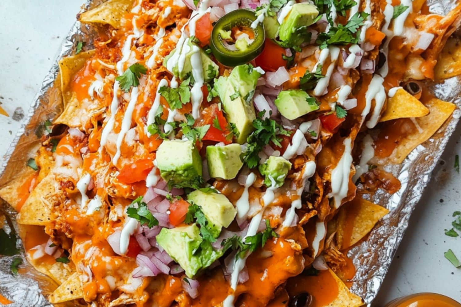 Buffalo chicken served on top of baking pan with sheet pan lined with aluminum foil.