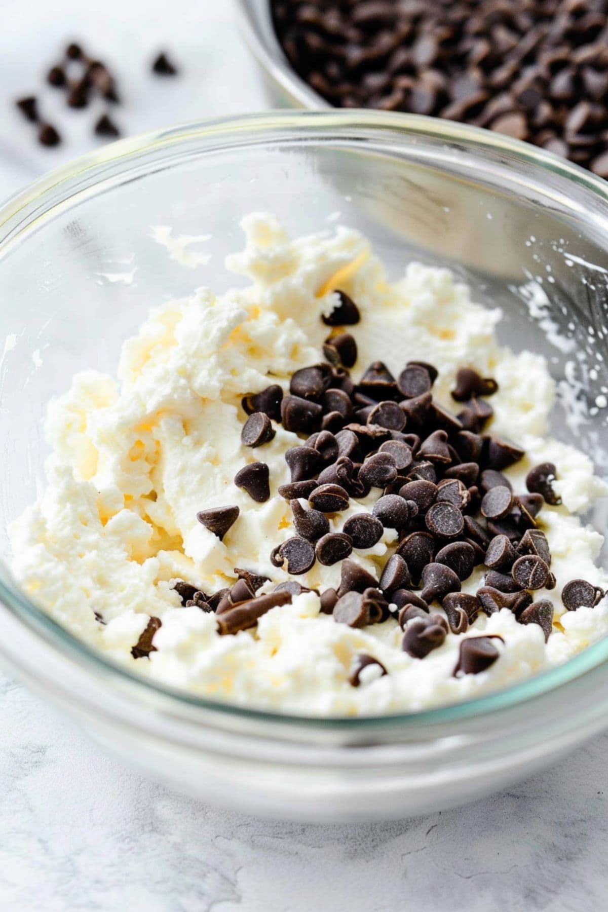 Ricotta cheese with mini chocolate chips in a glass bowl.