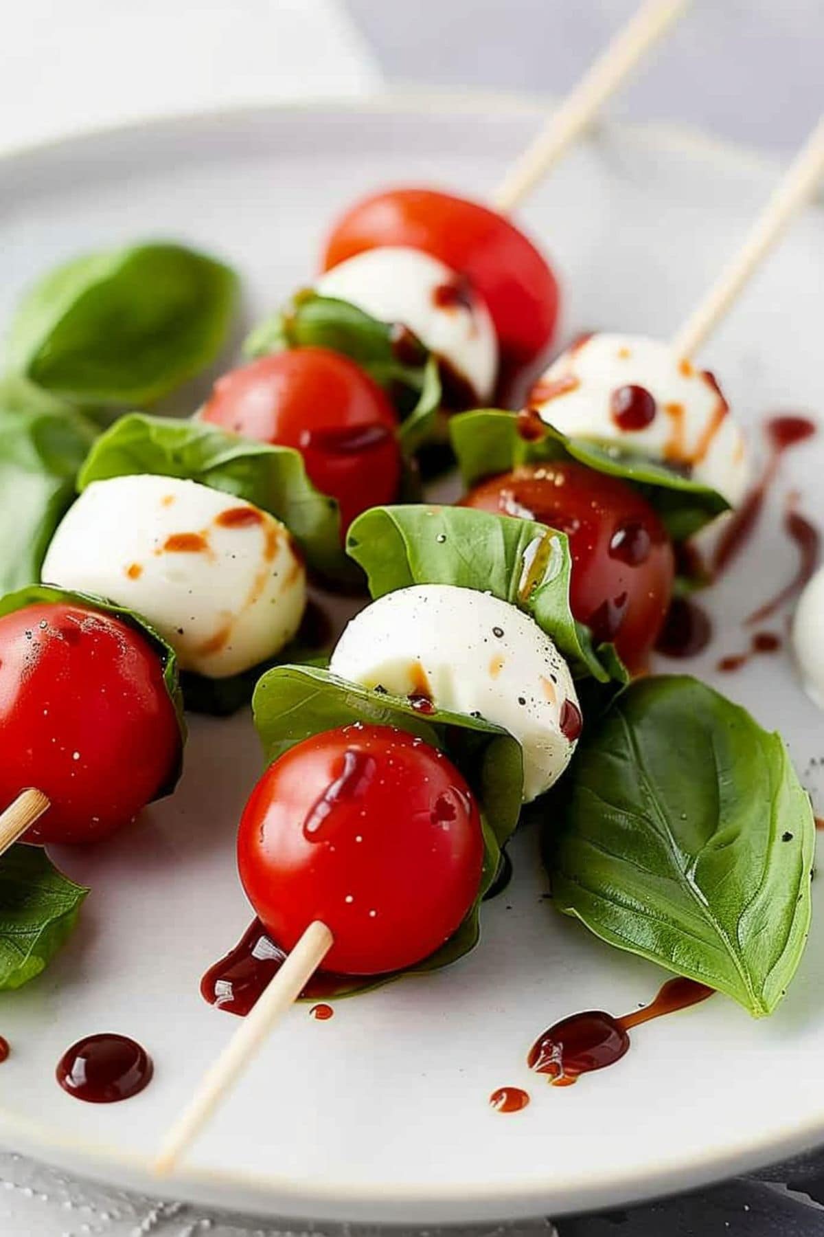 Mozzarella balls, fresh basils and cherry tomatoes skewered in wooden sticks. 