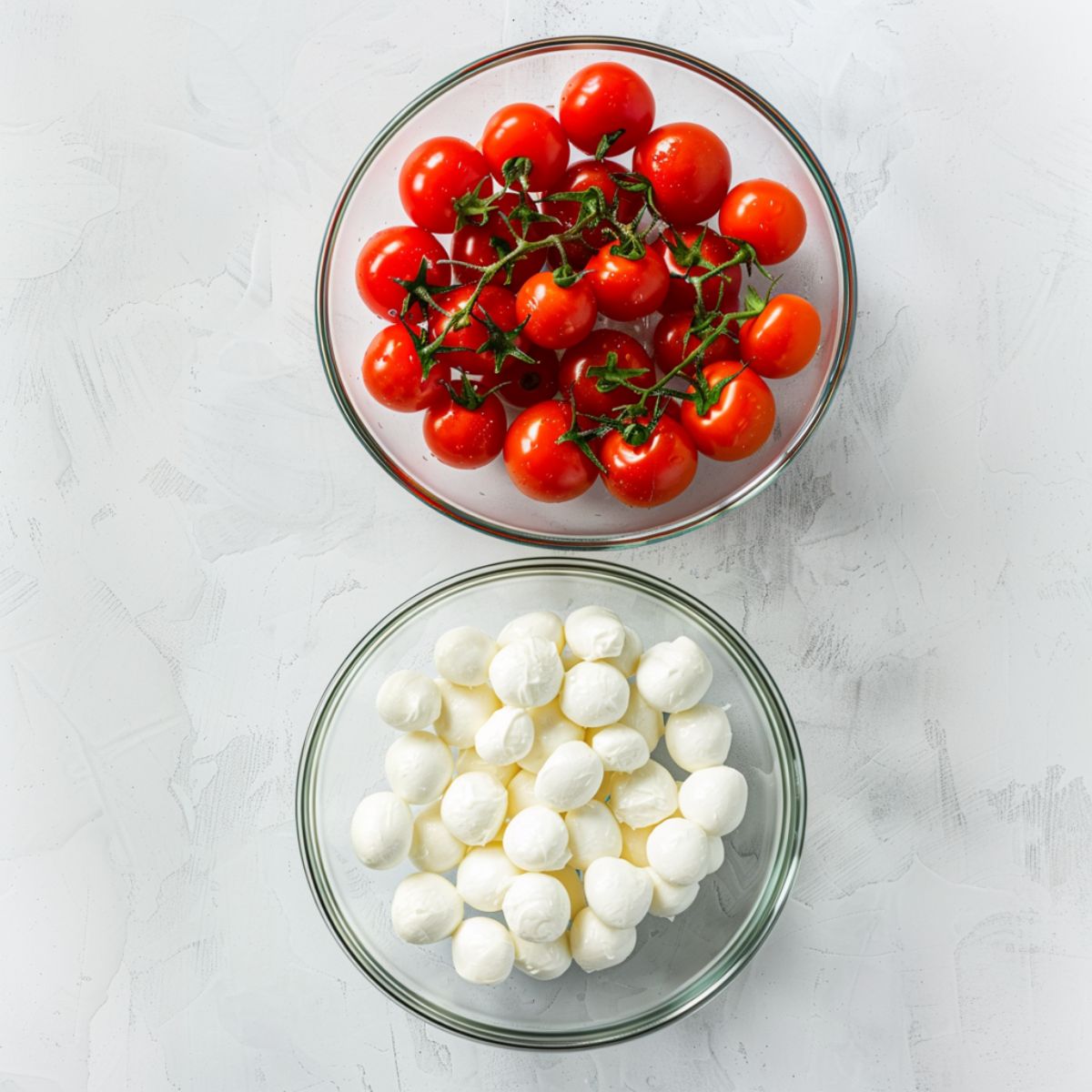 Cherry tomatoes and mozzarella balls in a glass bowl.