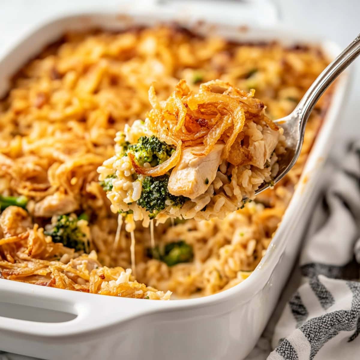 A baking dish filled with cheesy chicken broccoli rice casserole with fried onions.