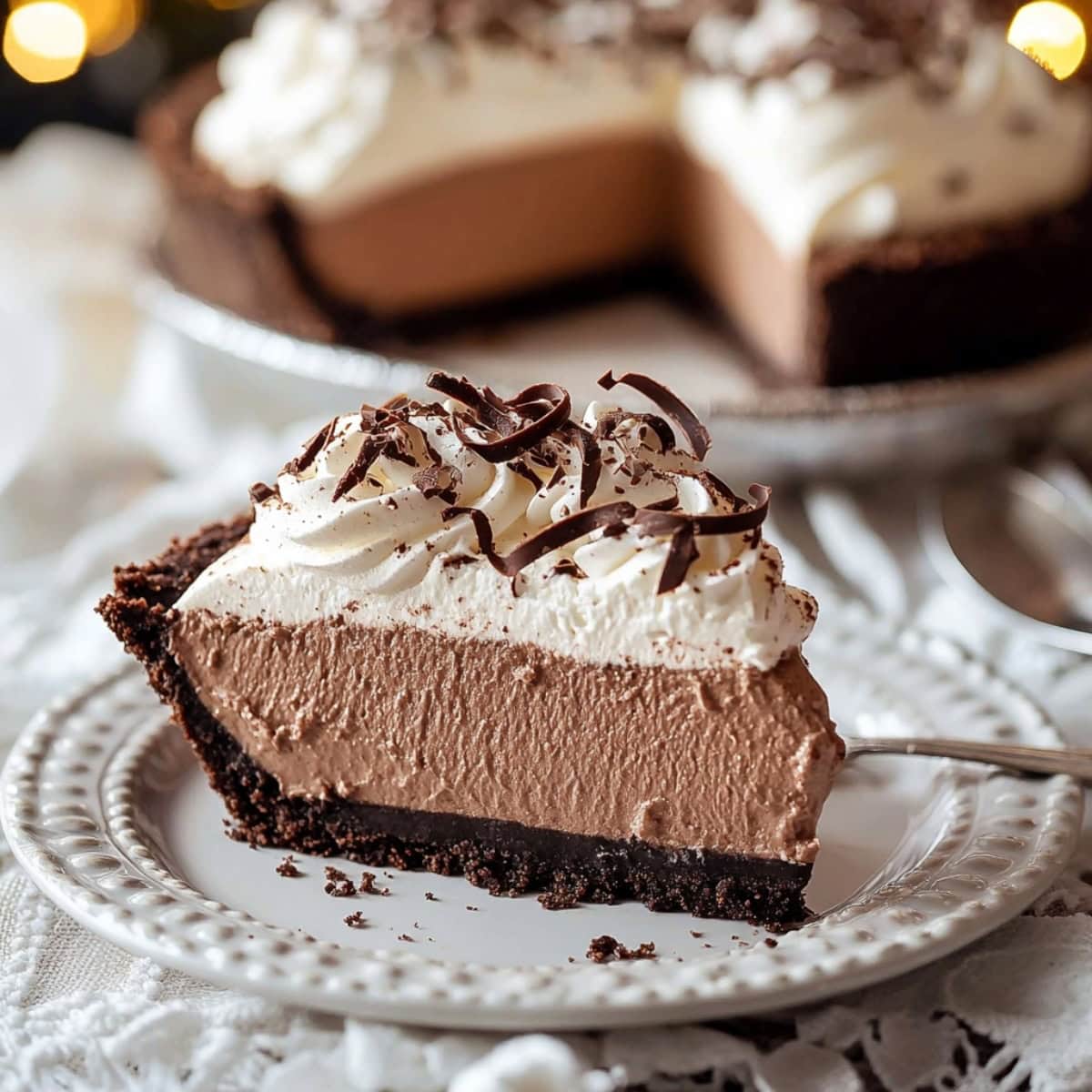 A slice of chocolate mousse pie with oreo cookie crust on a plate.