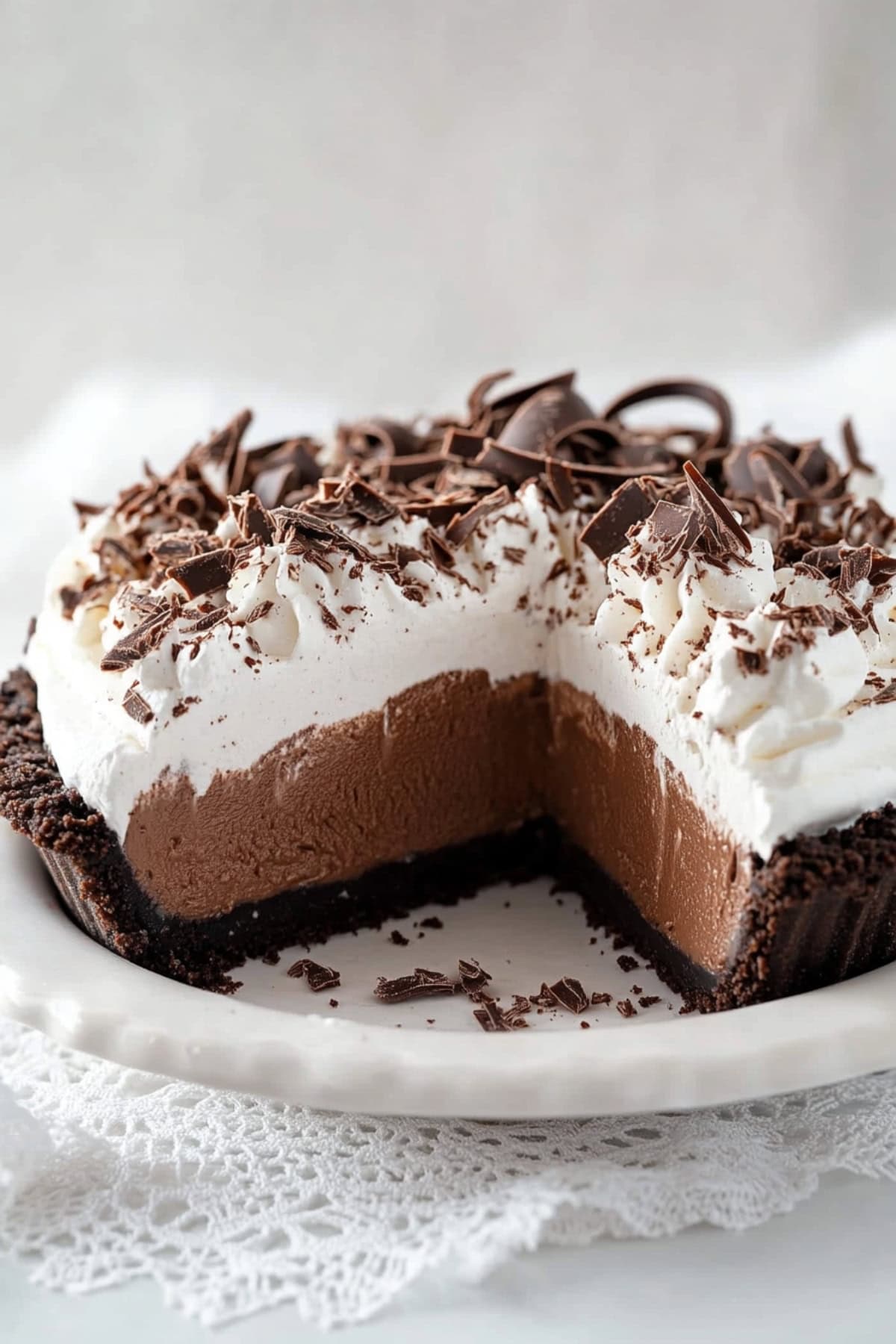 A close-up of chocolate mousse pie with whipped cream and chocolate shavings in a white pie dish
