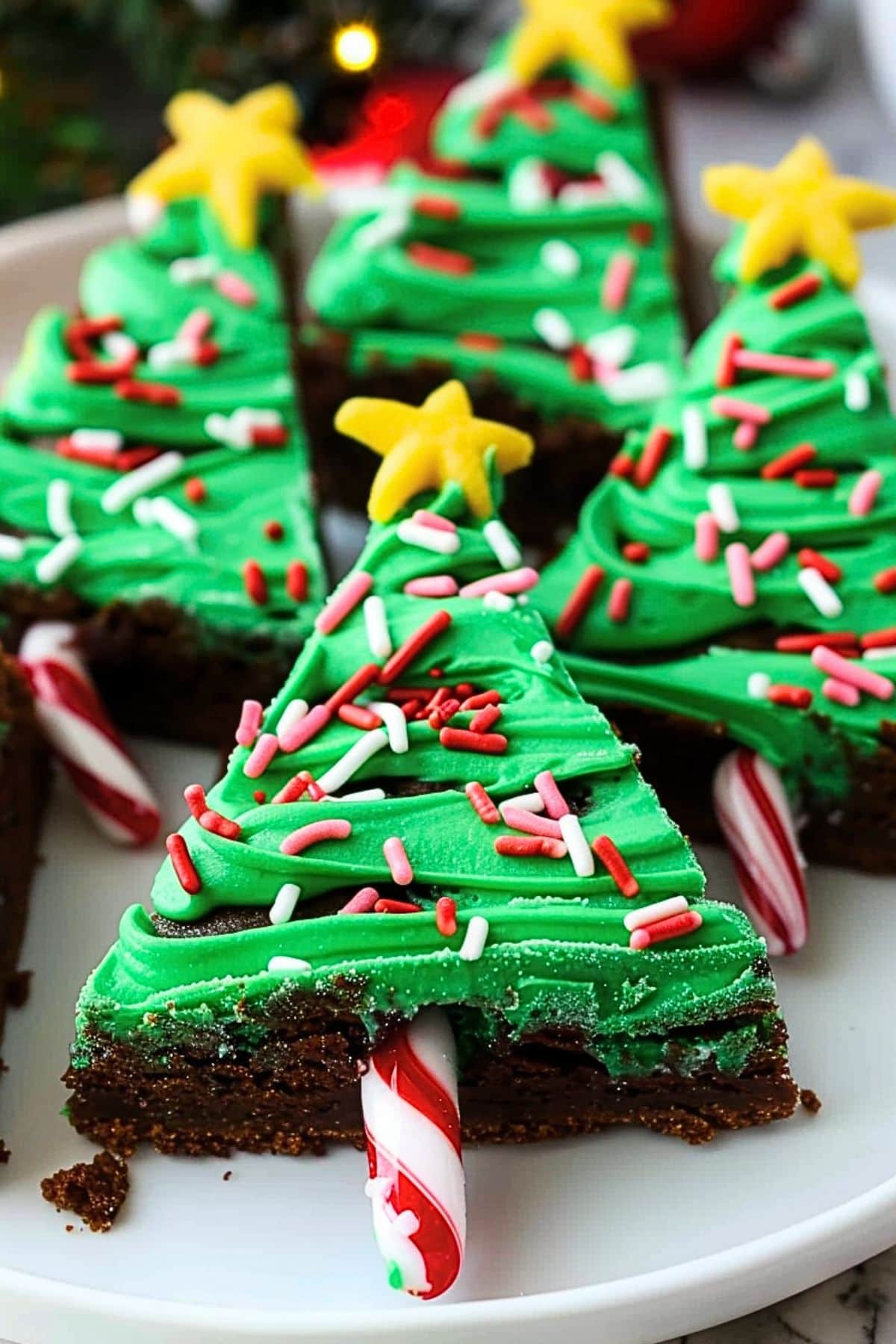 Christmas tree brownies with green frosting garnished with candy sprinkles.