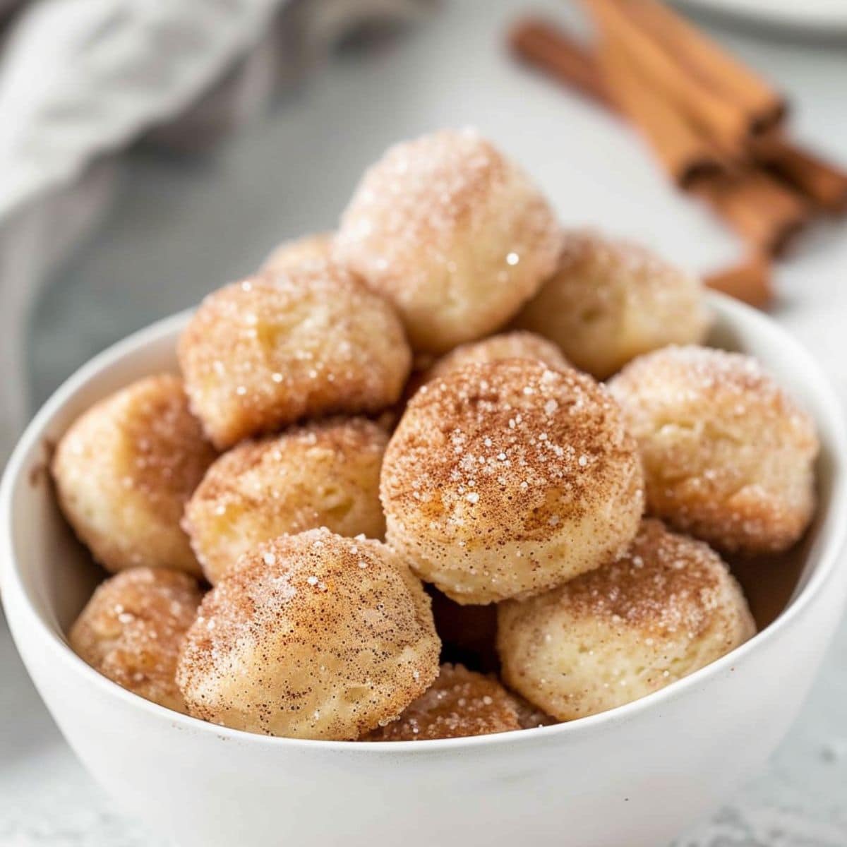 Biscuits bites coated with cinnamon sugar served in a white bowl.