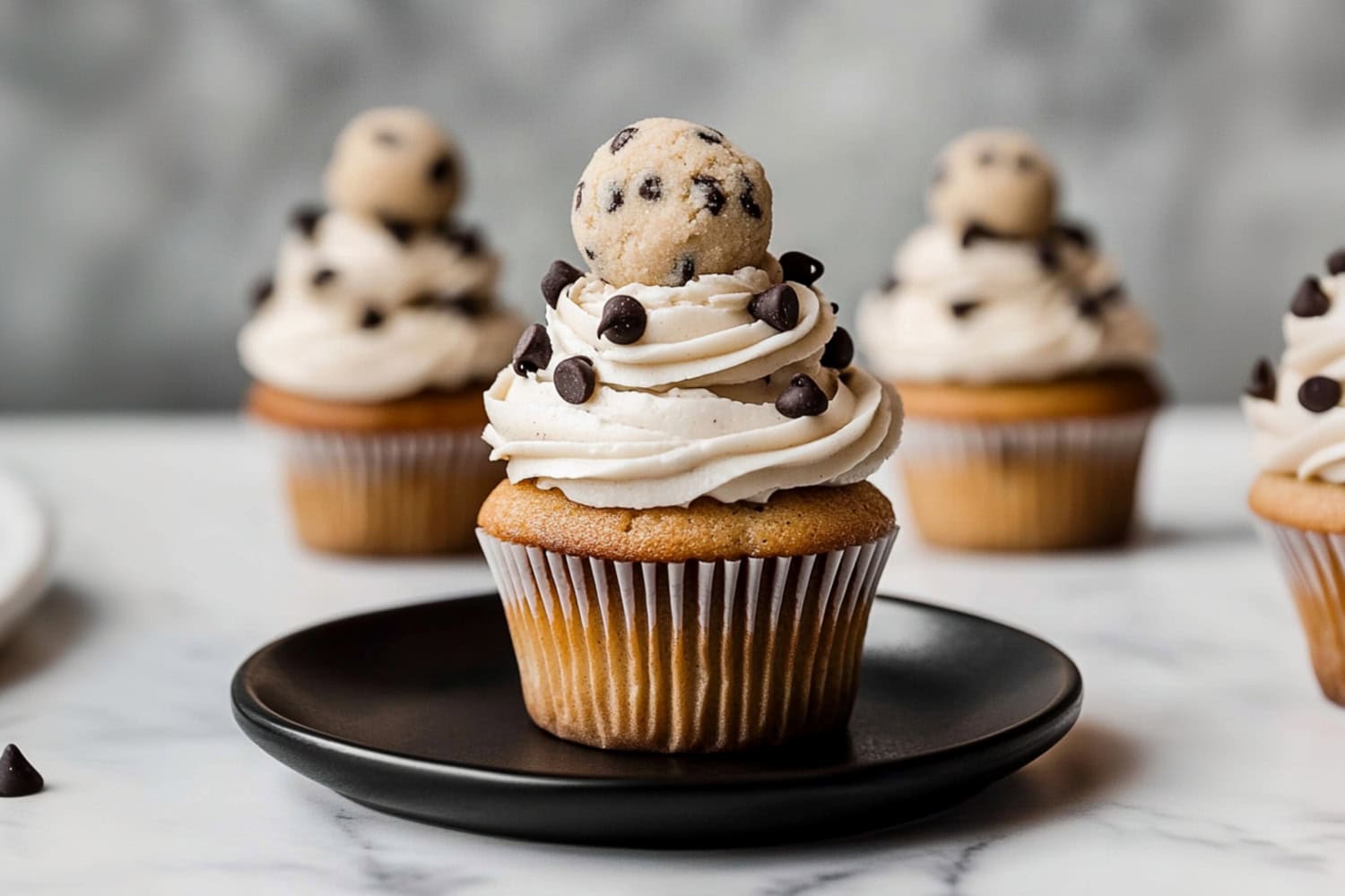 Homemade cookie dough cupcakes with vanilla frosting and chocolate chips in a black plate.