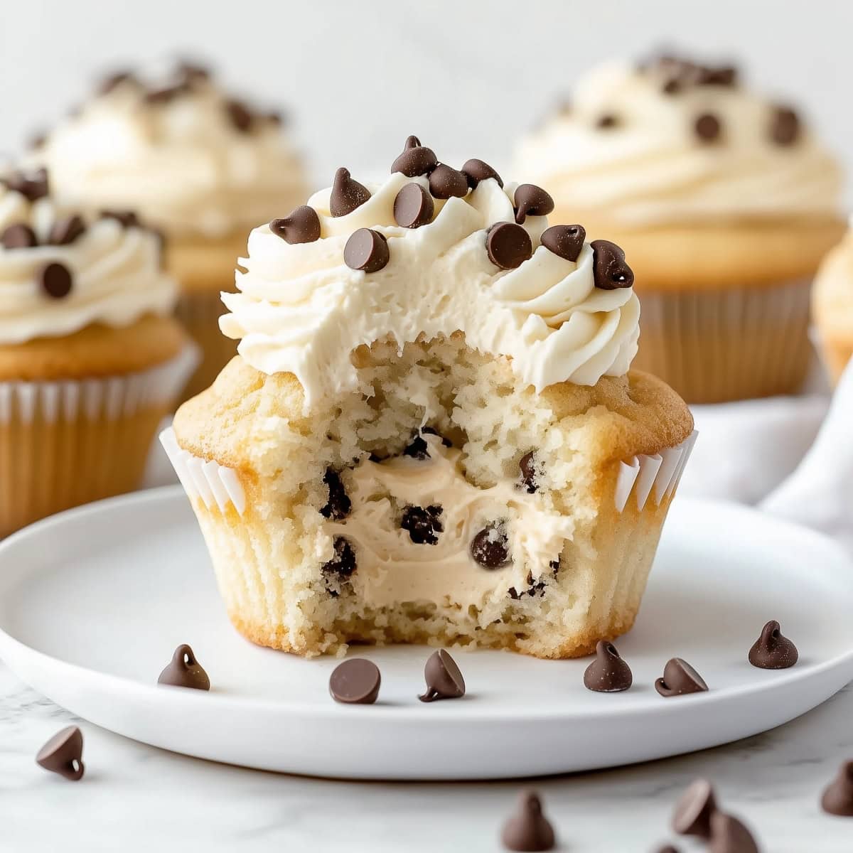 A vanilla cupcake with frosting cut in half to show the cookie dough filling. 