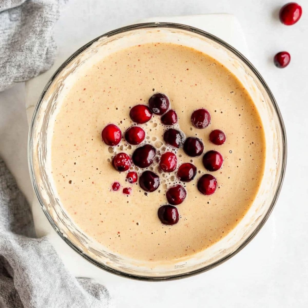 Pancake mix with fresh cranberries in a glass mixing bowl.