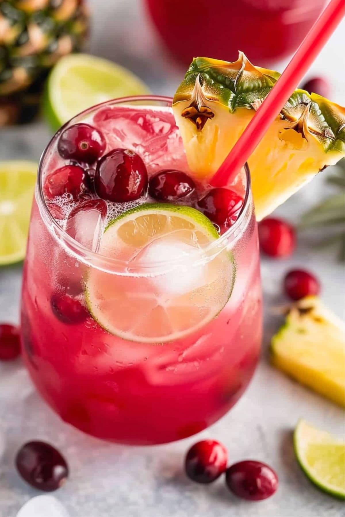 Refreshing serving of cranberry punch with fresh berries and lime garnished with pineapple slice.