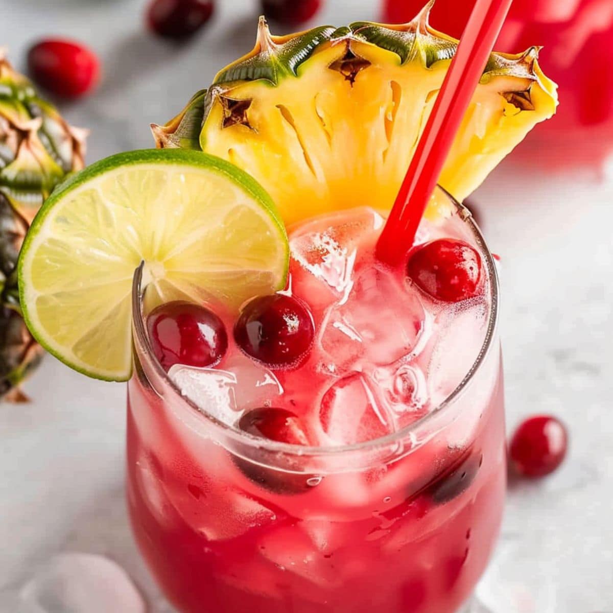 Cranberry pineapple punch garnished with lime and mixed with fresh cranberries served with ice in a glass.