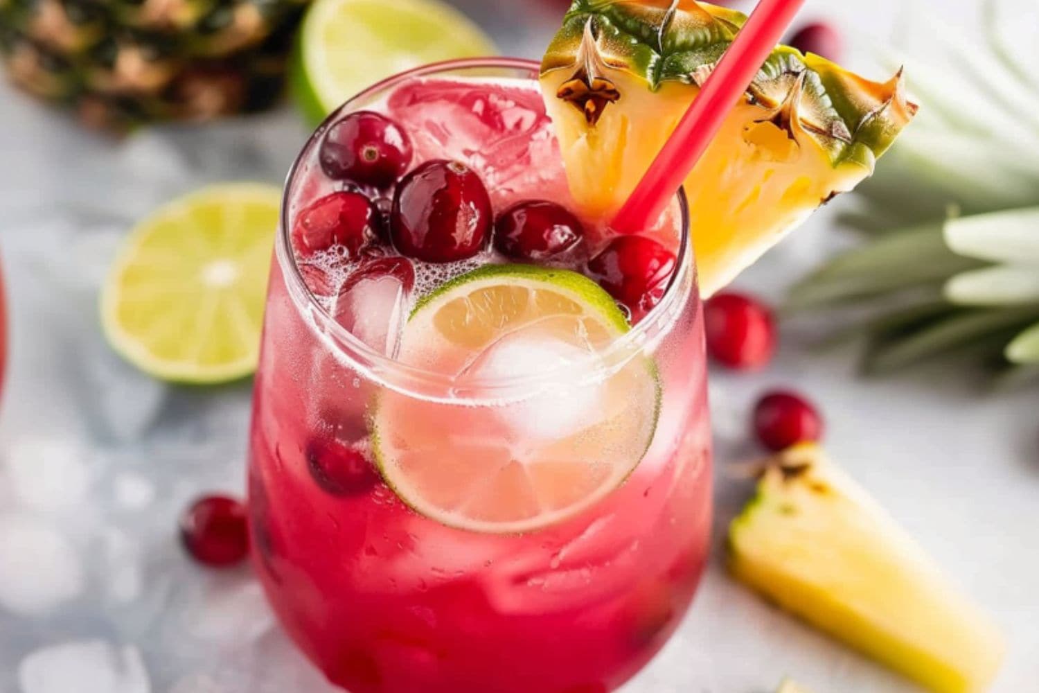 Serving of cranberry pineapple punch in a glass bowl decorated with pineapple slice.