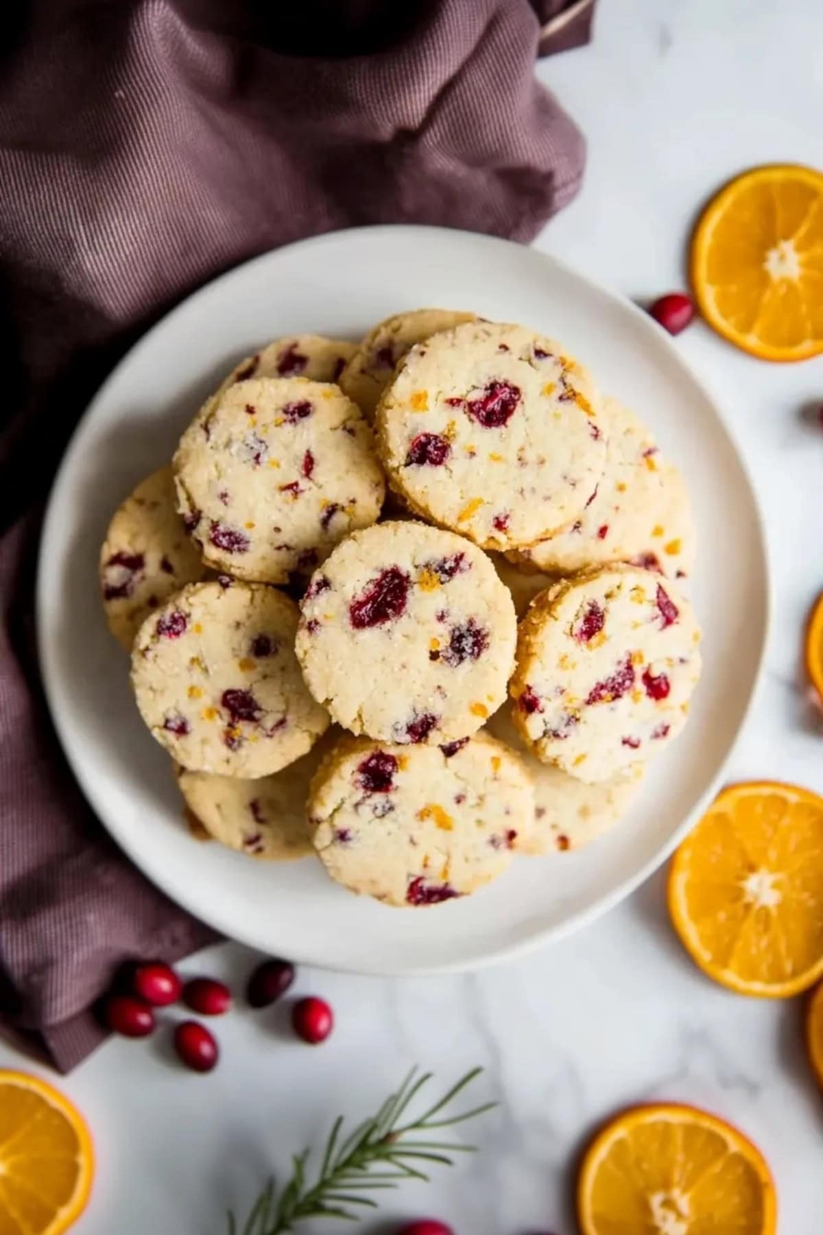 Freshly baked cranberry orange shortbread cookies arranged in a white plate, top view.