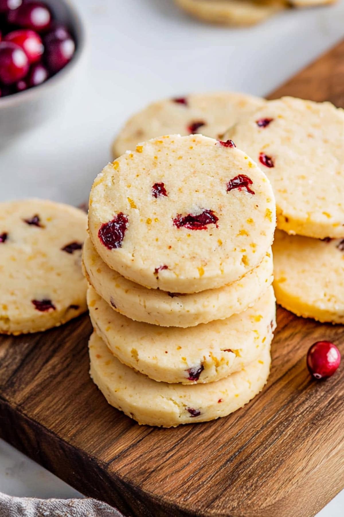 A stack of cranberry orange shortbread cookies in a wooden board.