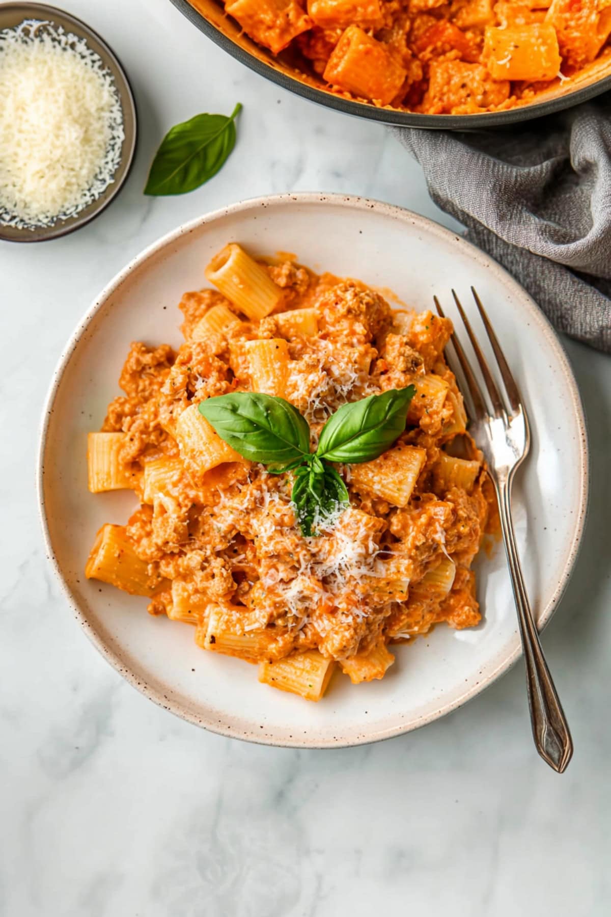 Homemade sausage rigatoni with parmesan and basil in a plate.