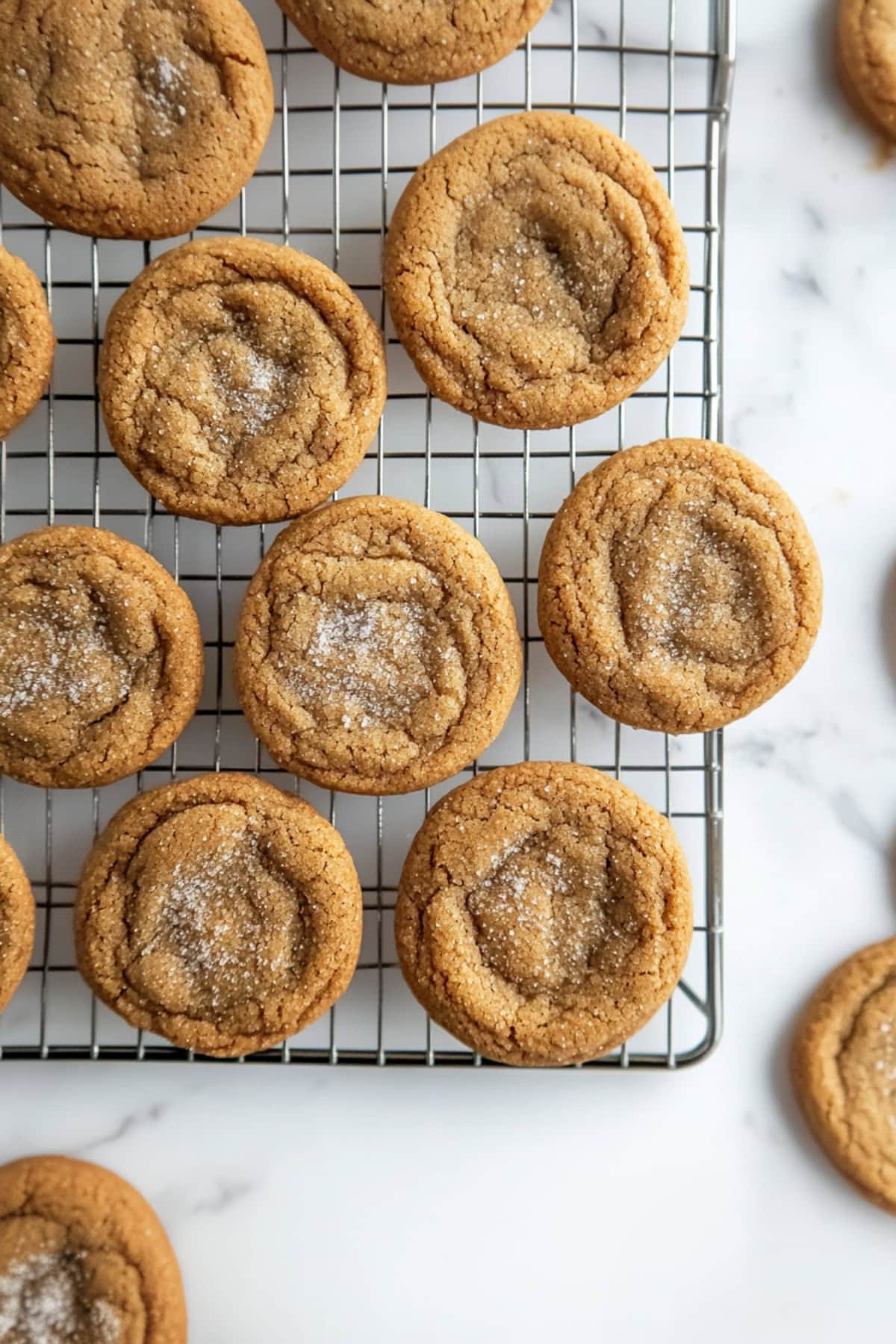 Warm ginger snickerdoodle cookies with sugar on a cooling rack.