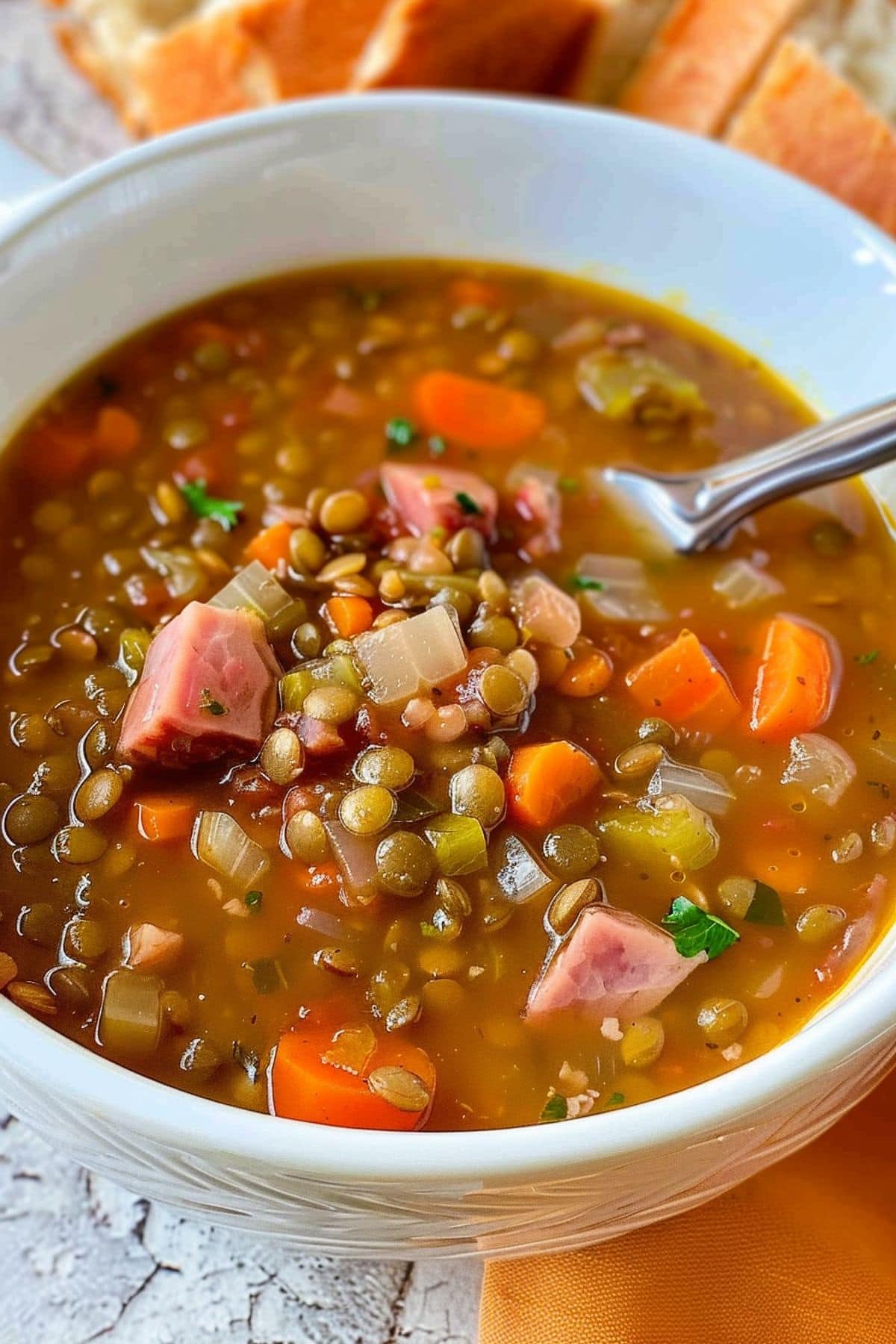 A serving of ham and lentil soup in a white bowl.