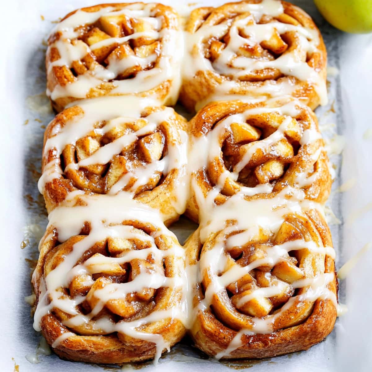 Freshly baked apple pie cinnamon rolls with a drizzle of sweet glaze.