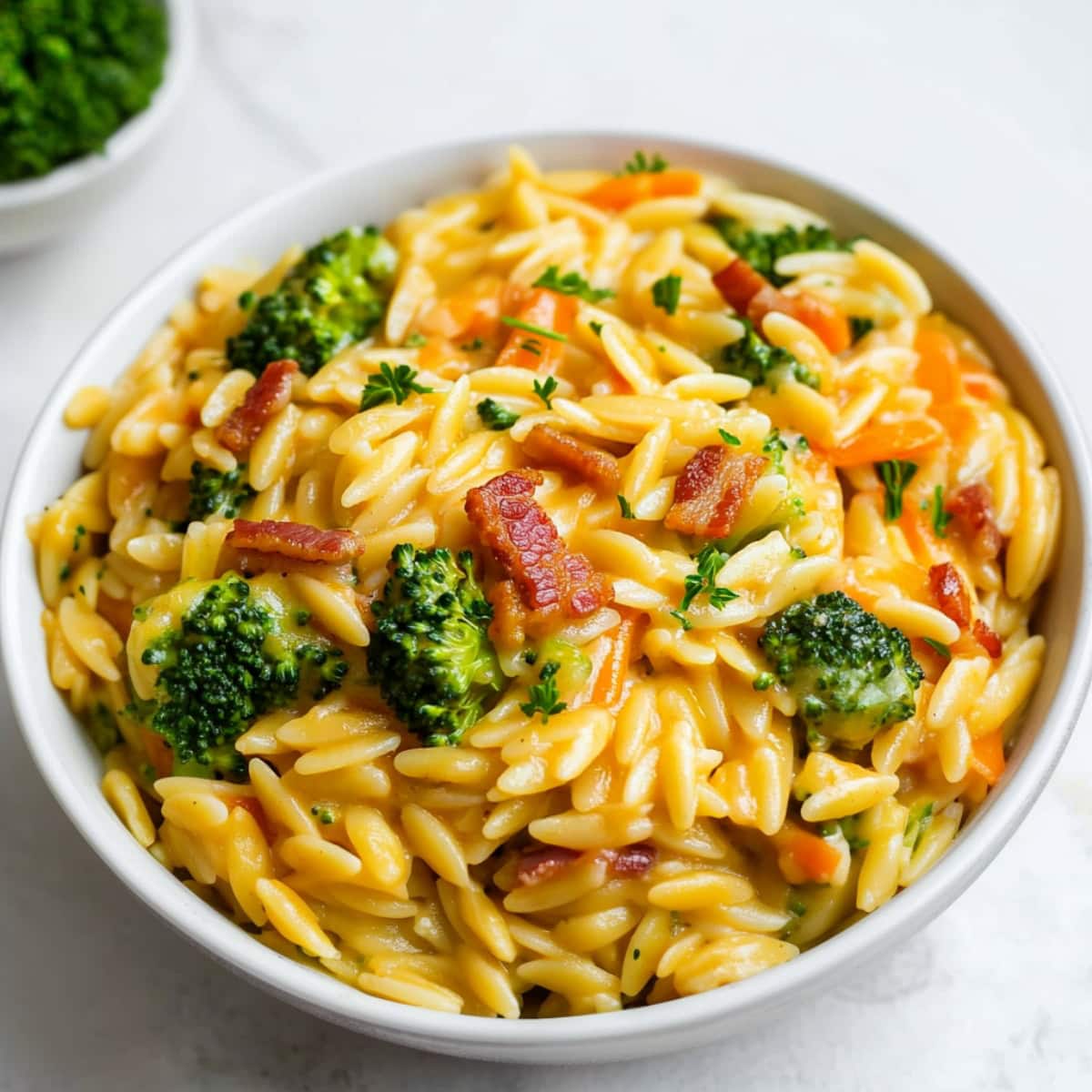 Homemade cheesy orzo with broccoli florets, bacon and carrots.